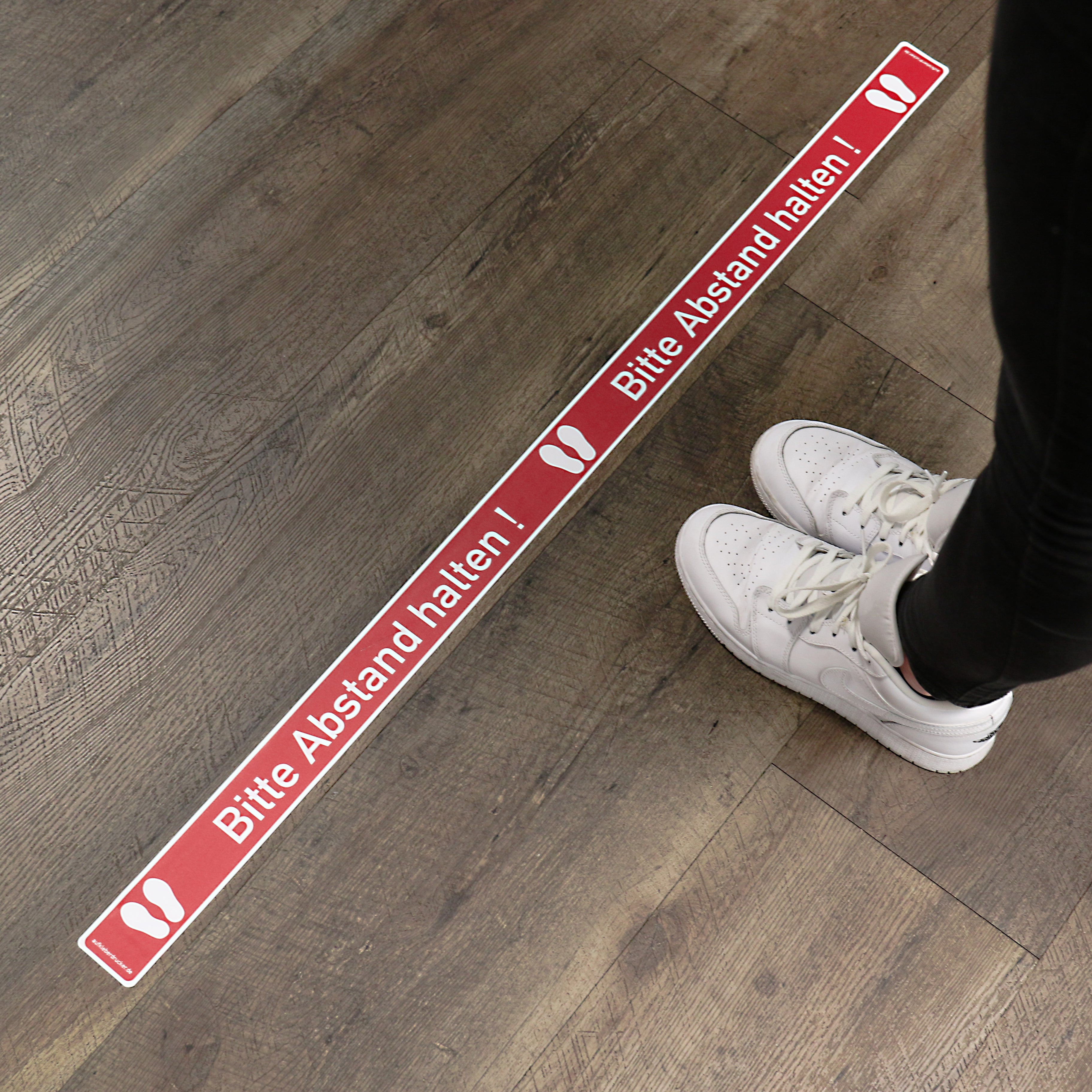 Roter Fußbodenaufkleber "Abstand halten" auf glatter Oberfläche, 1000x50 mm, 10 Stück, für sichere Wegeführung.