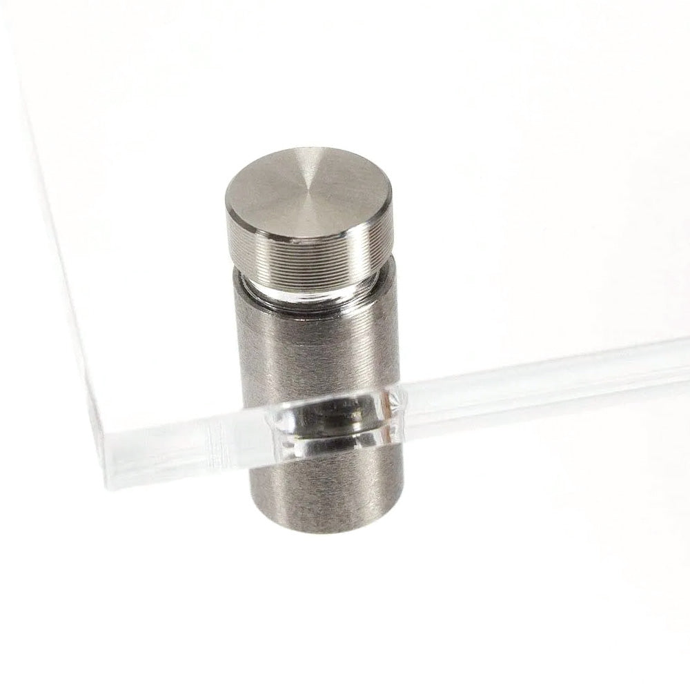 Vier Edelstahl-Abstandshalter 10 x 15 mm, schraubbar, auf einem stabilen Untergrund sichtbar.